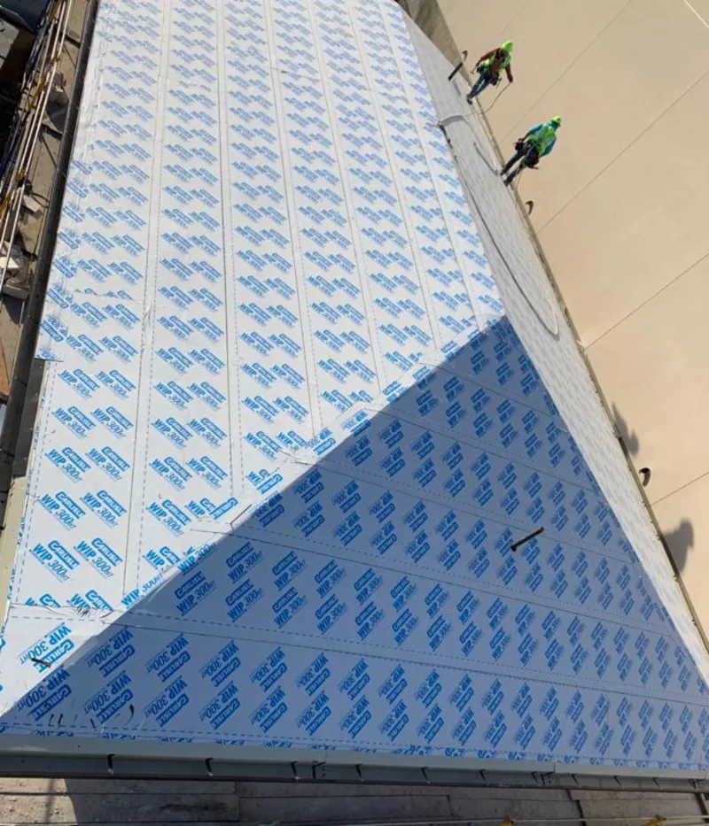 Professional roofers installing underlayment on a metal roof in Venersborg